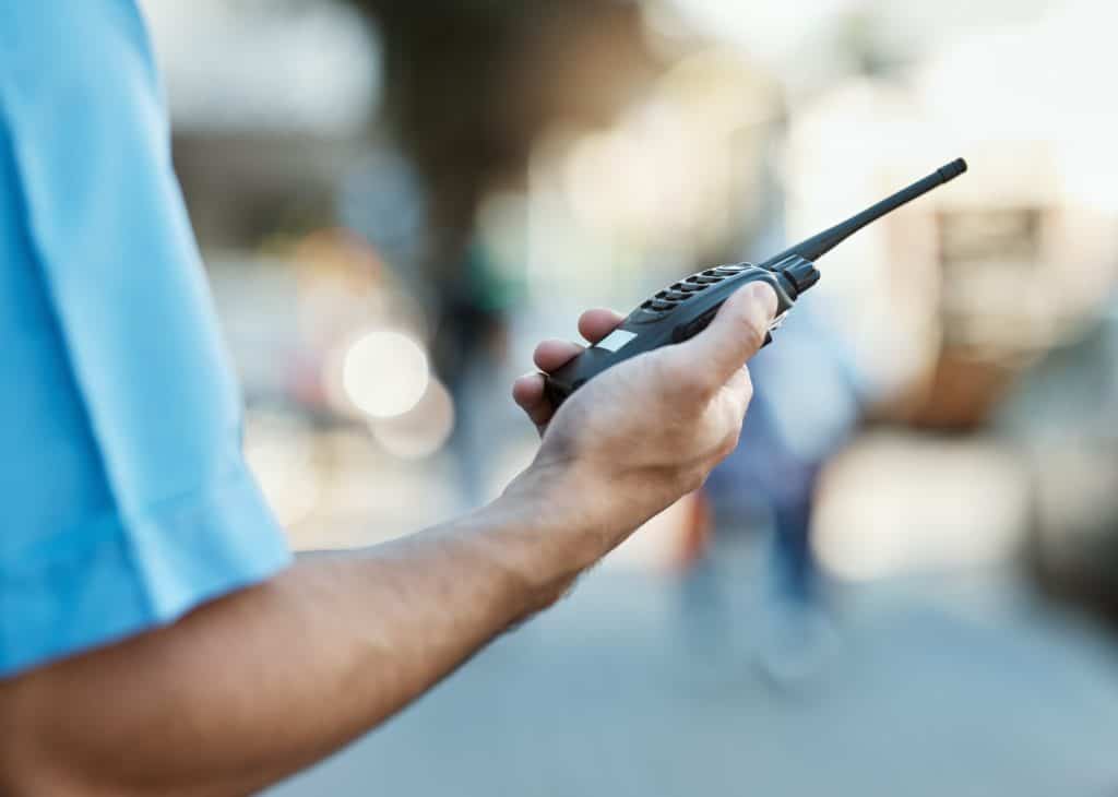 Close de uma pessoa com um walkie talkie em uma rua urbana