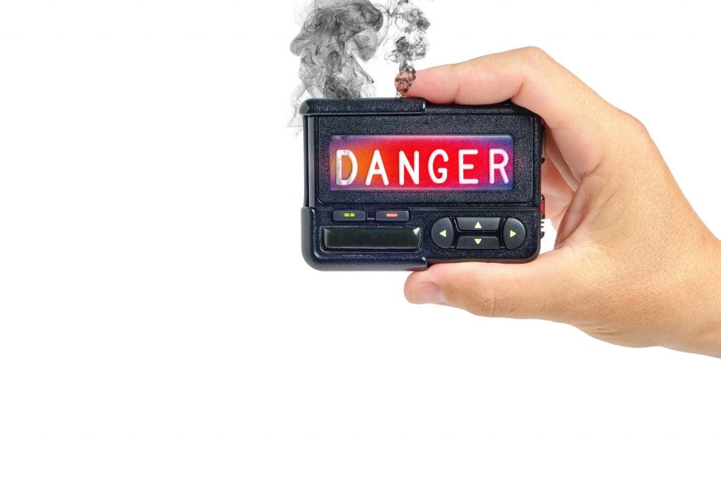 Imagem ilustrativa de mão segurando um pager com a mensagem "Danger", que significa "Perigo"