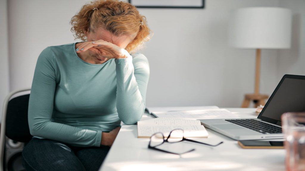 Mulher com dor de barriga, cólica, dor de cabeça, dor na cabeça, problemas e dificuldades de trabalhar em casa.