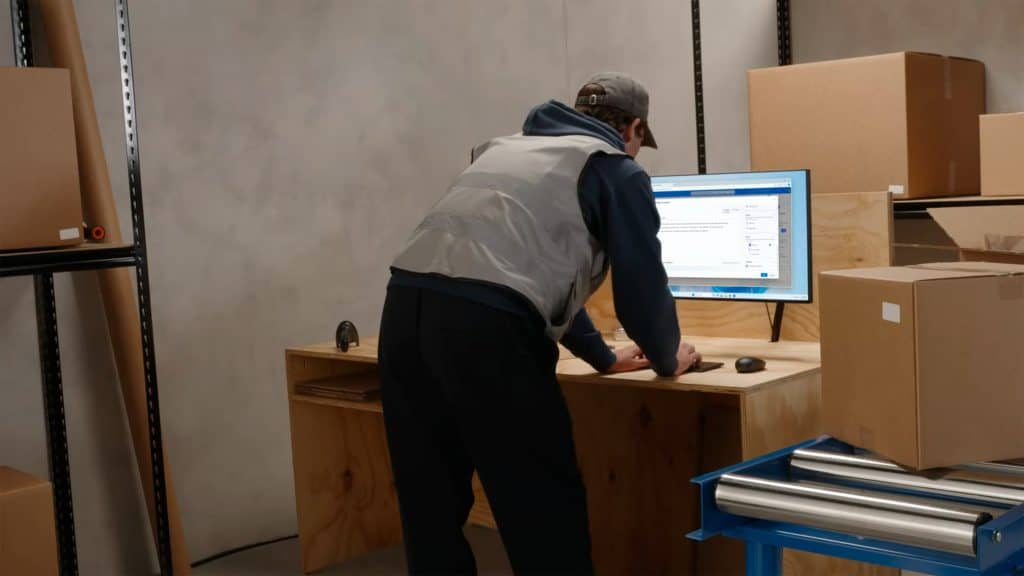 Homem de pé usando Windows 365 Link, PC que roda tudo na nuvem da Microsoft