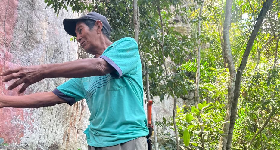 Jayme Caicedo apontando para a arte rupestre