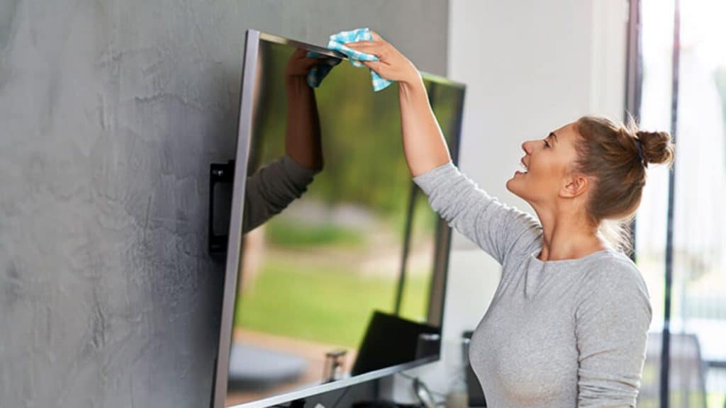 imagem mostra uma mulher limpando uma televisão