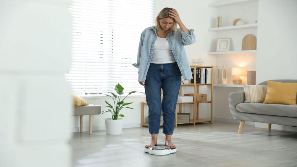 Você sabe o que causa a diabetes? A resposta vai além do açúcar A diabetes é uma doença caracterizada pelo aumento anormal de glicose no sangue e surge quando o organismo não consegue produzir insulina em quantidade suficiente ou não consegue utilizá-la de modo adequado. Mulher preocupada em pé em escalas de chão em casa