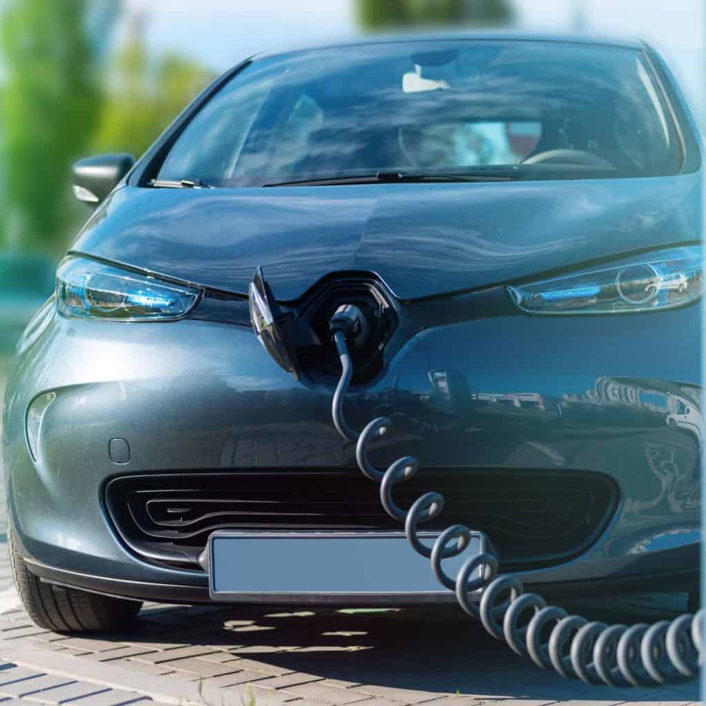 Um carro elétrico moderno conectado a uma estação de carregamento, com o cabo de recarga inserido na lateral do veículo.
