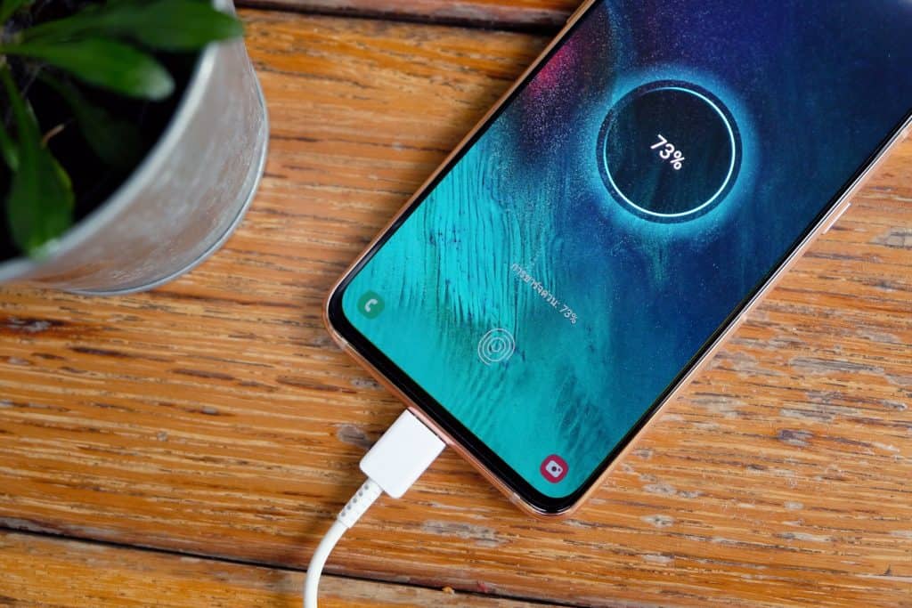 Celular Android com cabo de carregamento e porcentagem na tela 