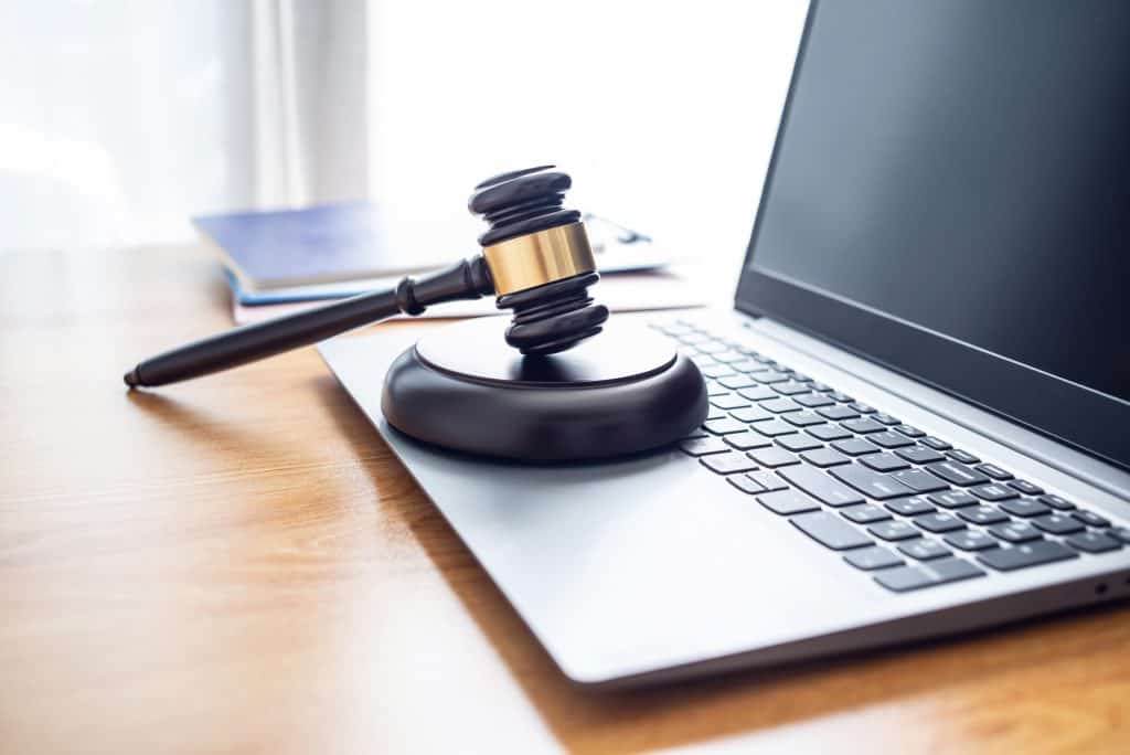 Martelo de leiloeiro sobre uma base que está em cima do teclado de um notebook