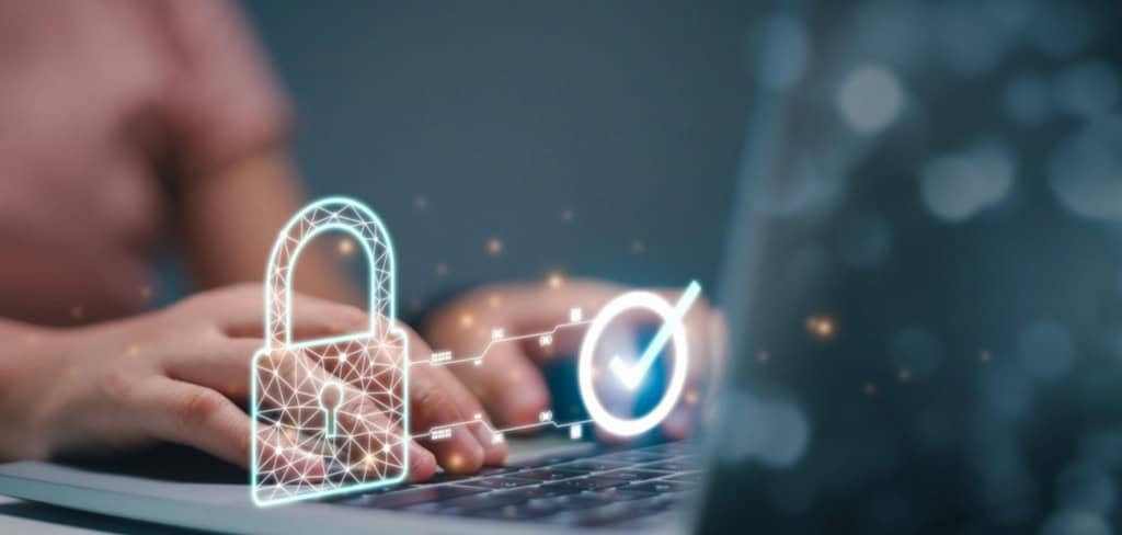 pessoa digitando em notebook, arte com cadeado e sinal de certo, indicando invasão de dados, algo do tipo.