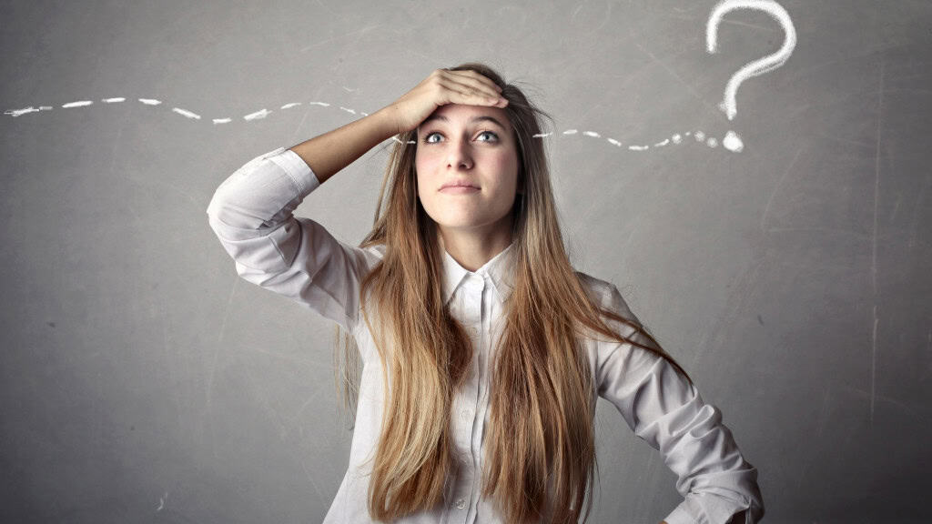 O oposto do déjà vu acontece – e é ainda mais estranho de se sentir O déjà vu é uma das experiências mais intrigantes do cérebro humano. Trata-se da sensação estranha de já ter vivido uma situação inédita, como se o momento atual fosse uma repetição de algo que nunca aconteceu. Mulher loira tentando lembrar, com símbolo de interrogação ao fundo; referência à falta de memória
