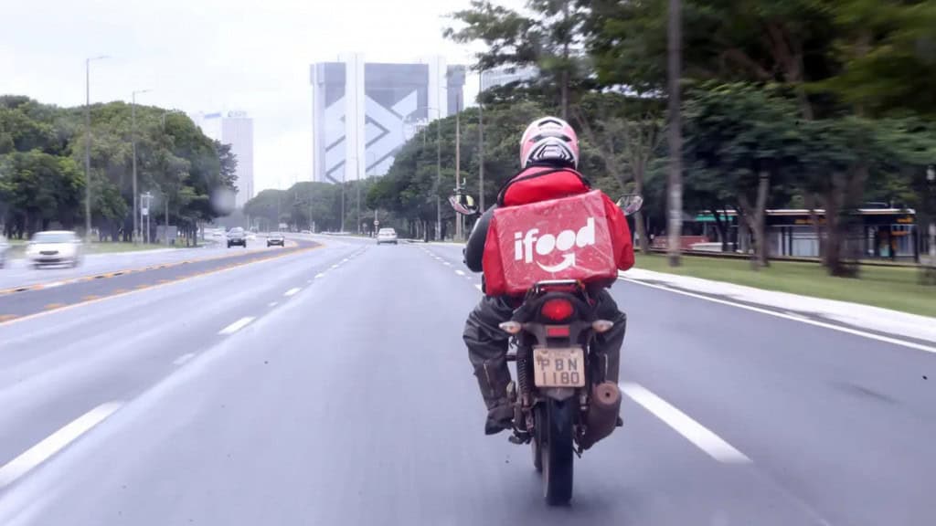 Motoboy com mochila do iFood andando em avenida de São Paulo