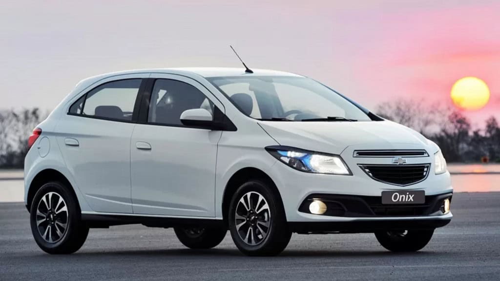 Qual o momento ideal para trocar de carro? Nos últimos anos no Brasil, escolher o momento para trocar de carro se tornou uma decisão difícil em razão do salto nos preços, desvalorização do Real e mudança nas legislações. Mas como a gente se planeja para decidir pela troca no tempo certo? foto do carro Onix na versão branca com o por do sol atrás