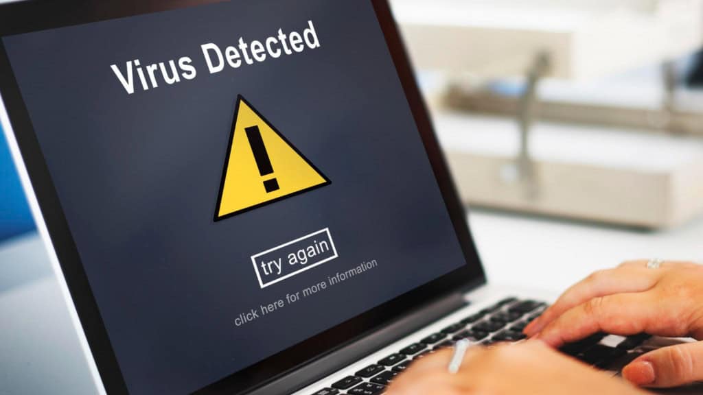 pessoa usando um laptop que tem uma mensagem de vírus na tela