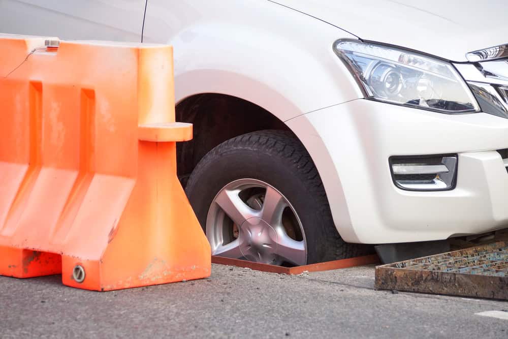 Estacionar sobre uma tampa de bueiro dá multa? Veja o que diz a lei Ao estacionar o seu carro em uma rua, pode acontecer de você deixar a roda do veículo em cima de uma tampa de bueiro. Apesar de parecer uma ação normal, isso é capaz de gerar prejuízos para o seu automóvel e ainda dar dores de cabeça com as autoridades de trânsito. Pneu