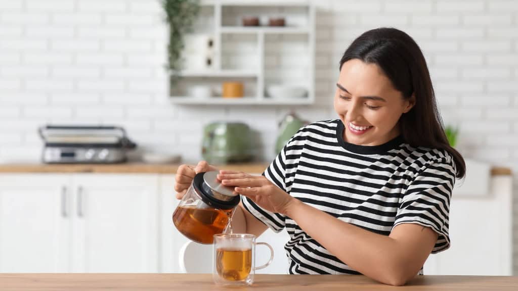 7 hábitos comuns que afetam seu fígado e podem causar problemas de saúde Com a missão de realizar inúmeras funções importantes, o segundo maior órgão do corpo humano demanda cuidados constantes. No entanto, o que muitos não sabem é que alguns hábitos silenciosos são os responsáveis por prejudicar ou sobrecarregar o fígado, acarretando problemas de saúde ao longo da vida. Linda jovem mulher feliz derramando chá quente de chaleira transparente em xícara na cozinha