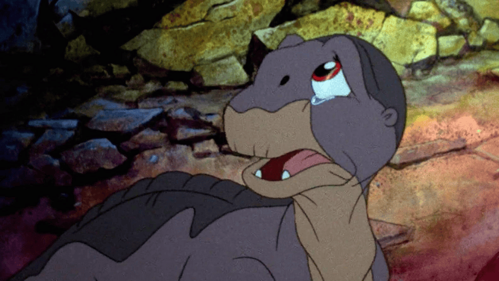 10 filmes de animação que parecem fofos, mas são bem pesados Quando pensamos em filmes de animação, nossa mente geralmente faz uma ligação direta com personagens queridos e coloridos, enredos encantados e um mundo cheio de alegria – sem contar que muitas vezes o formato é associado a conteúdo para crianças. No entanto, a verdade é que a animação também é cinema. Cena da animação "Em Busca do Vale Encantado" com bebê dinossauro chorando
