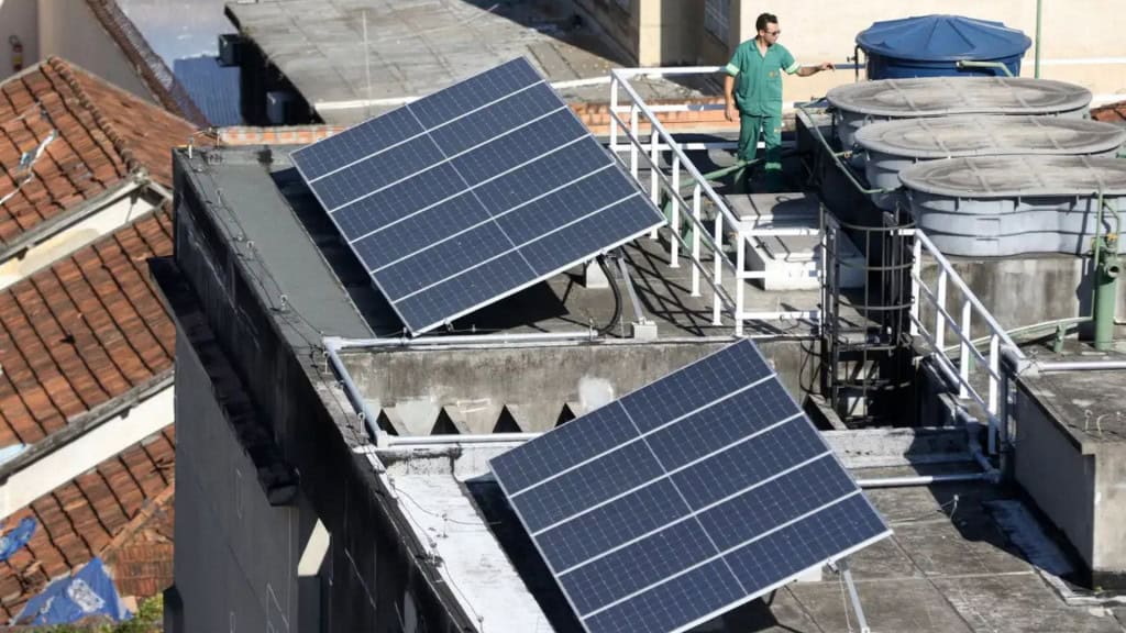 Paineis de energia solar inclinados com técnico do lado em telhado de prédio