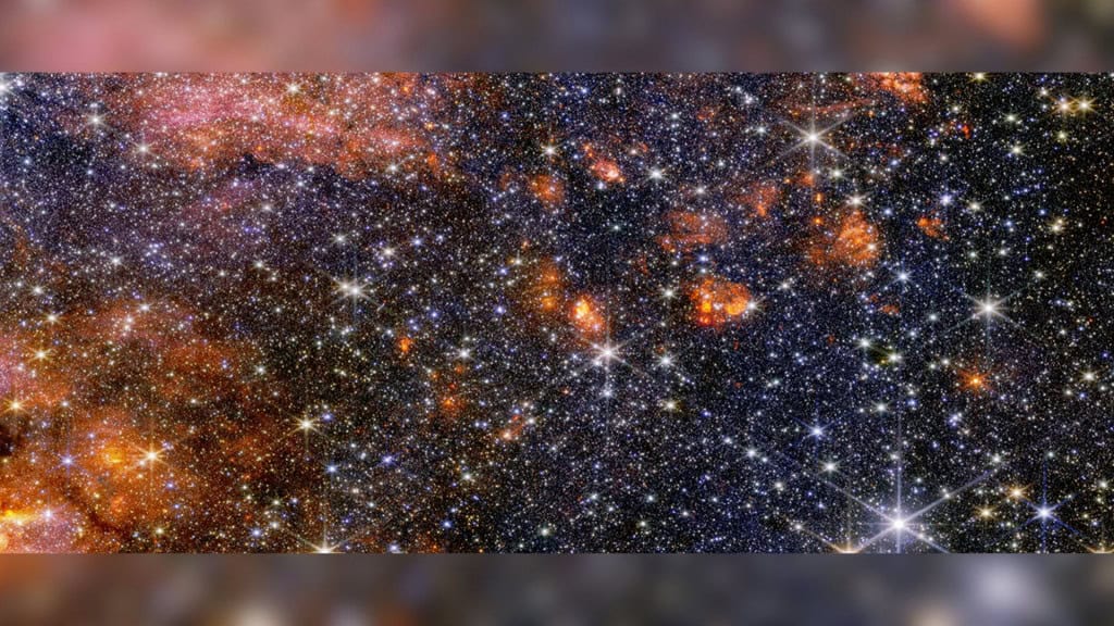 James Webb revela segredos do maior berçário estelar da Via Láctea O telescópio espacial James Webb capturou imagens inéditas da Sagittarius B2, a maior nuvem formadora de estrelas da Via Láctea. Localizada a poucas centenas de anos-luz do buraco negro central da galáxia, essa região imensa concentra poeira cósmica, gás e estrelas em formação numa escala que astrônomos nunca tinham visto com tanto detalhe. Estrelas, gás e poeira cósmica na nuvem de Sagitário B2 capturadas pelo telescópio James Webb