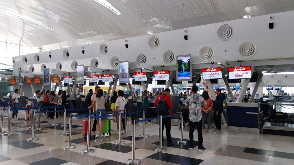 fila com várias pessoas em balcões de atendimento para realizar check-in em um aeroporto