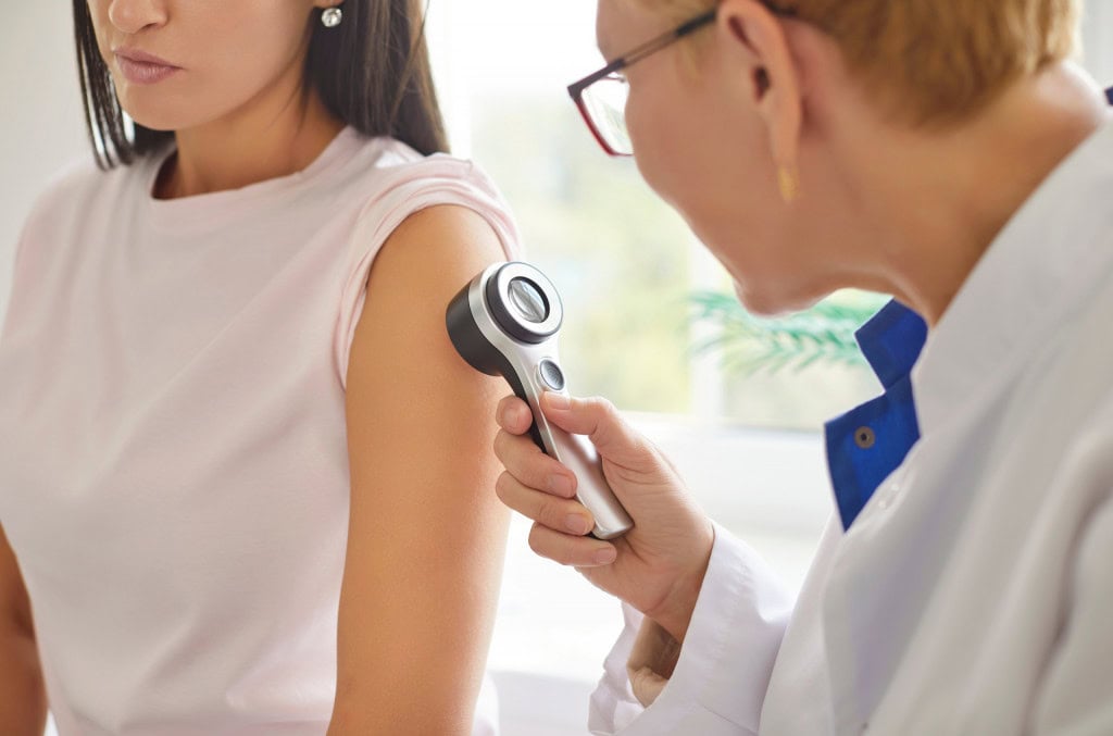 Médico usando um aparelho para examinar a pele de uma mulher