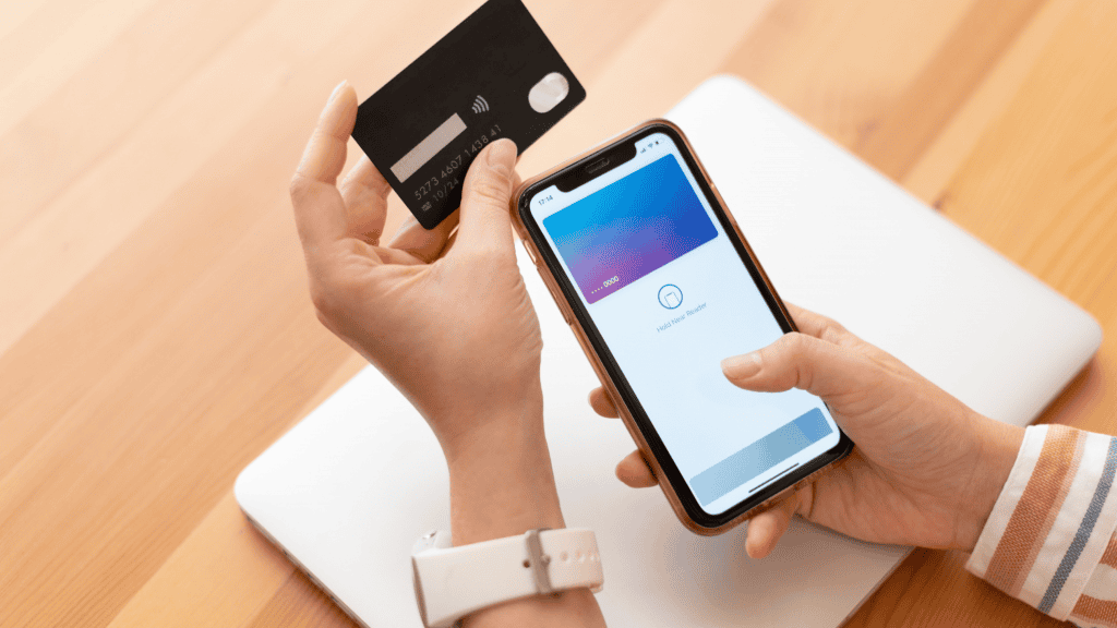 Carteira digital vale a pena? Entenda os aplicativos Google Wallet e Apple Pay As carteiras digitais já se tornaram uma realidade no dia a dia de milhões de pessoas, revolucionando a forma como realizamos pagamentos e guardamos informações financeiras. mulher segurando o celular enquanto adiciona o cartão em uma carteira digital