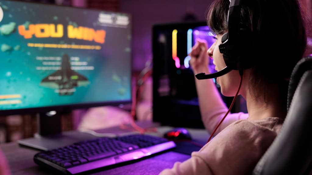 Meninos estão cada vez mais no videogame; devemos nos preocupar? Nas últimas décadas, os videogames deixaram de ser passatempo para se tornarem um dos principais espaços de socialização entre meninos. Gamer comemorando vitória em jogo online de naves, animada em apartamento com luzes RGB /