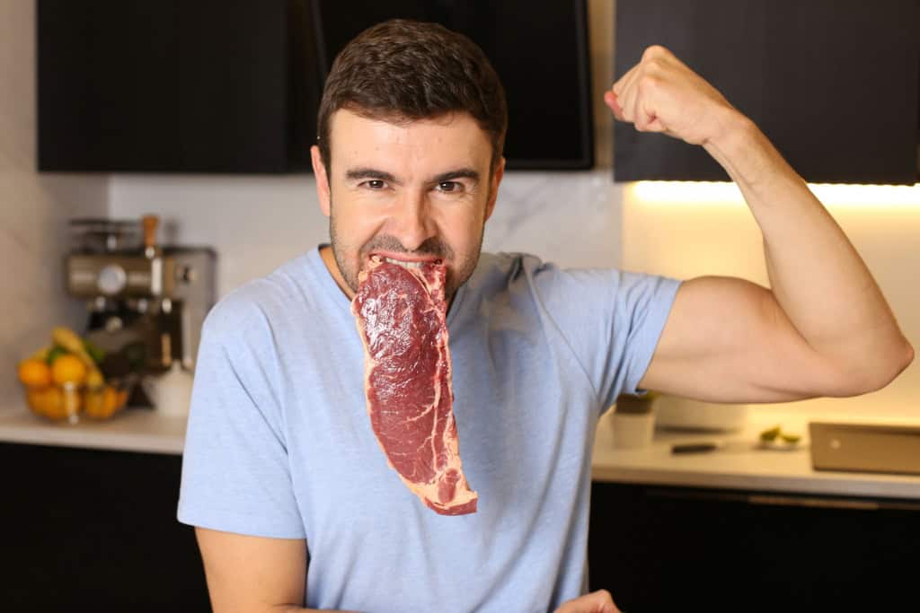 7 hábitos comuns que afetam seu fígado e podem causar problemas de saúde Com a missão de realizar inúmeras funções importantes, o segundo maior órgão do corpo humano demanda cuidados constantes. No entanto, o que muitos não sabem é que alguns hábitos silenciosos são os responsáveis por prejudicar ou sobrecarregar o fígado, acarretando problemas de saúde ao longo da vida. Homem com um bife cru na boca enquanto mostra os músculos do braço
