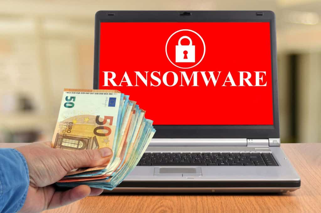 Imagem ilustrativa de conceito de pagamento de ransomware com um maço de notas e um laptop