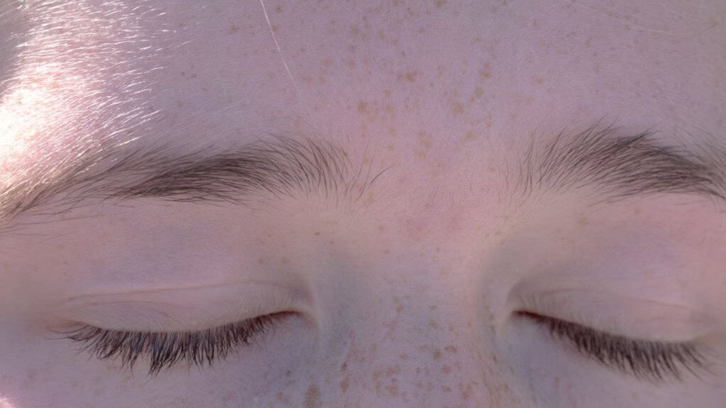 Close no rosto de uma pessoa com sardas e olhos fechados