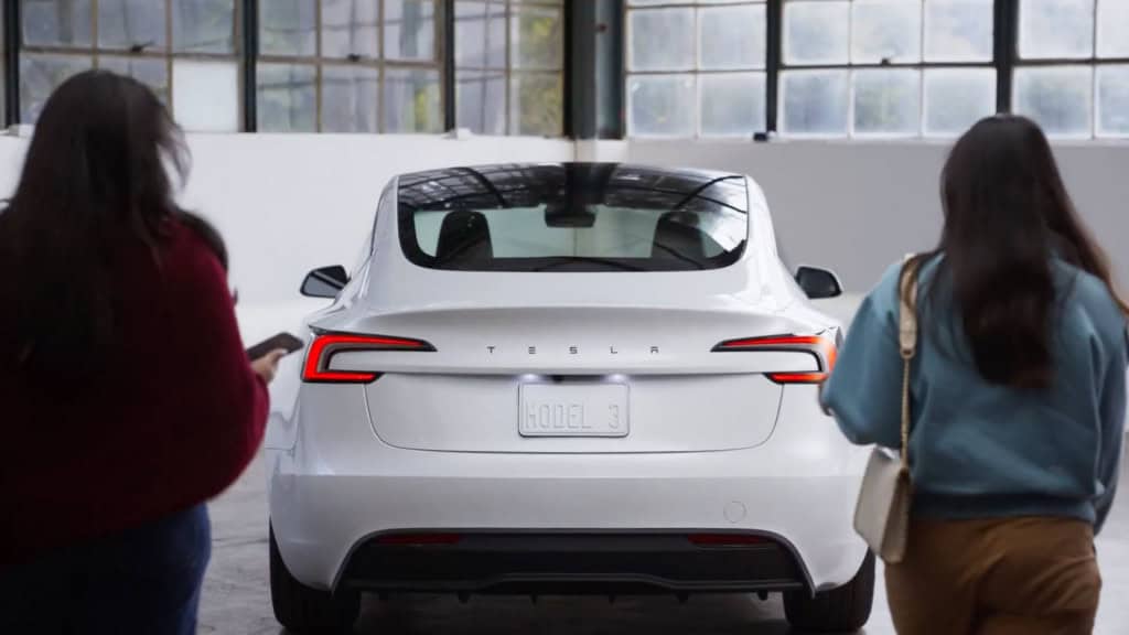 Com versões ‘peladas’ do Model 3 e Y, Tesla tenta se recuperar de ano fraco A Tesla apresentou nesta semana versões mais baratas de seus dois modelos mais vendidos: o sedã Model 3 e o SUV Model Y. Chamadas de Standard, elas chegam ao mercado americano com preços a partir de US$ 37 mil e US$ 40 mil (cerca de R$ 208 mil e R$ 225 mil, respectivamente – em conversão direta). São valores aproximadamente US$ 5 mil abaixo das versões de entrada anteriores. Duas mulheres se aproximando do novo Model 3 Standard da Tesla