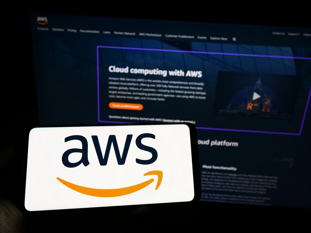 Falha da AWS fez camas inteligentes travarem durante a madrugada Usuários de colchões inteligentes da Eight Sleep tiveram uma madrugada inesperada devido à falha nos servidores da Amazon Web Services (AWS), que deixou diversos serviços fora do ar na segunda-feira (20). Enquanto bancos, plataformas de jogos e equipamentos de ginástica enfrentavam instabilidades, alguns donos das camas conectadas relataram que os dispositivos ficaram presos em posição inclinada, apresentaram temperaturas fora de controle ou ativaram alarmes sozinhos. Ao fundo, site da AWS; à frente, smartphone na horizontal com o logo da AWS