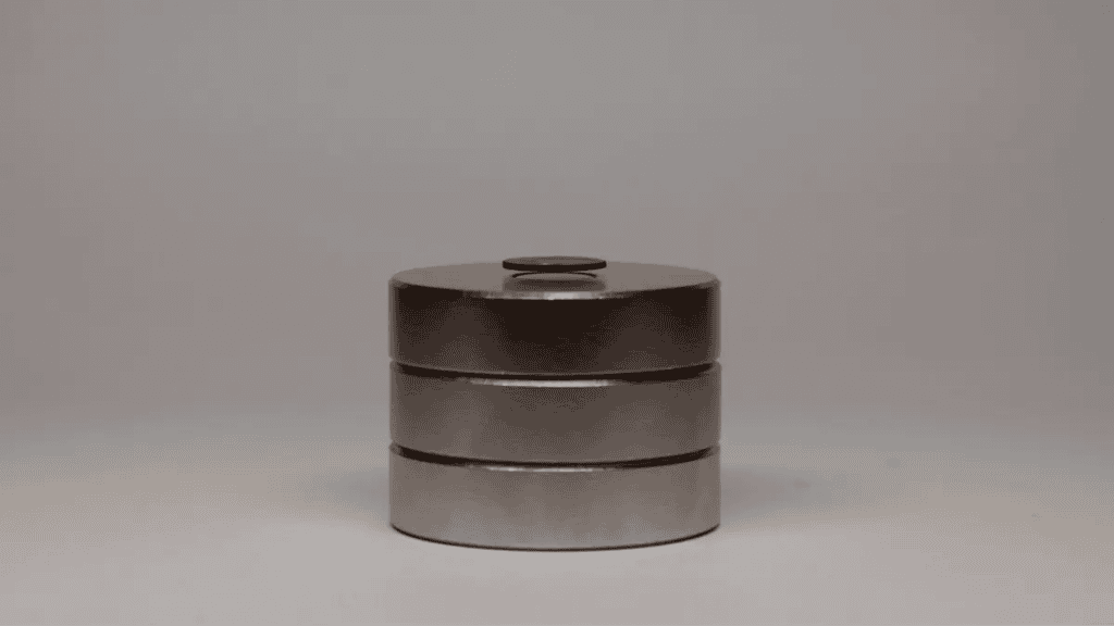 Disco de grafite preto levitando sobre três ímãs redondos empilhados