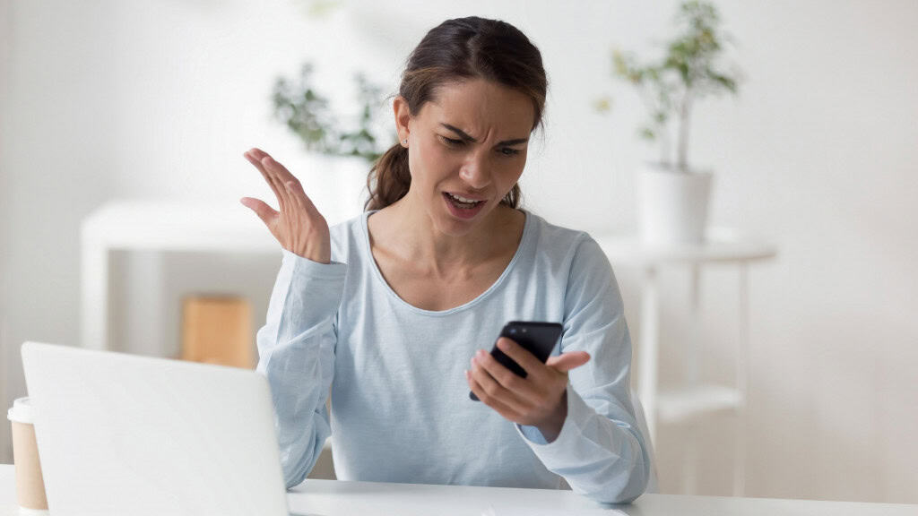 Mulher jovem frustrada olhando para o celular
