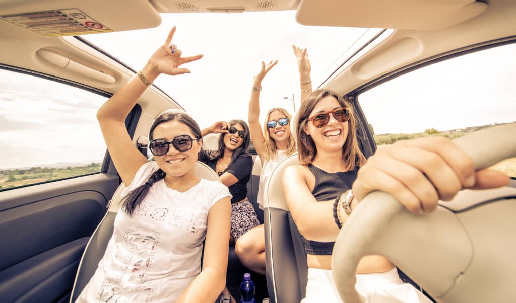 12 dicas tech para espantar o tédio em viagens de carro, ônibus e avião Viajar pode ser incrível, mas quem nunca ficou olhando pela janela, torcendo para o tempo passar mais rápido? Seja de carro, ônibus ou avião, a tecnologia pode ser a sua melhor companhia para transformar horas paradas em momentos produtivos, divertidos ou relaxantes. Quatro mulheres se divertem com música em um carro.
