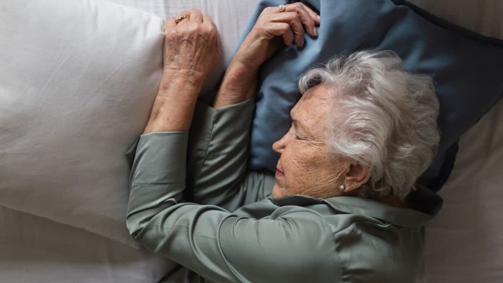 Falta de sono pode reduzir a expectativa de vida mais do que dieta e exercício A correria do fim de ano, marcada por prazos apertados, compromissos extras e confraternizações, costuma cobrar um preço alto das rotinas de descanso. No entanto, noites curtas e mal dormidas vão além do cansaço imediato e podem afetar diretamente a expectativa de vida. Um estudo realizado nos Estados Unidos aponta que a falta de sono é um dos fatores que mais reduzem a longevidade, ficando atrás apenas do tabagismo e superando impactos associados à dieta, à atividade física e até à solidão. Mulher idosa dormindo em sua cama, vista superior