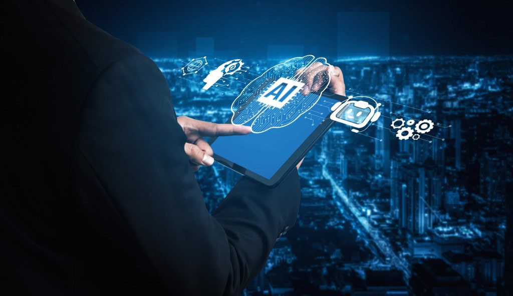 Nvidia divulgará balanço financeiro nesta semana; o que esperar? Durante a conferência GTC, realizada em Washington no mês passado, o CEO da Nvidia, Jensen Huang, afirmou que a companhia tem um volume de negócios em carteira que gira na casa de meio trilhão de dólares até agora. Pessoa com um tablet na mão, cuja tela está projetando, no ar, um cérebro, que possui um chip com os dizeres "AI"