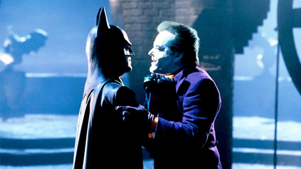 Batman em cena de filme segurando o Coringa pelo colarinho de seu terno. 