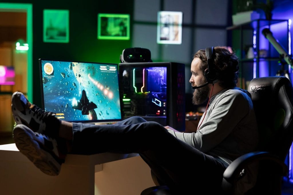 Homem sentado jogando videogame de headphone