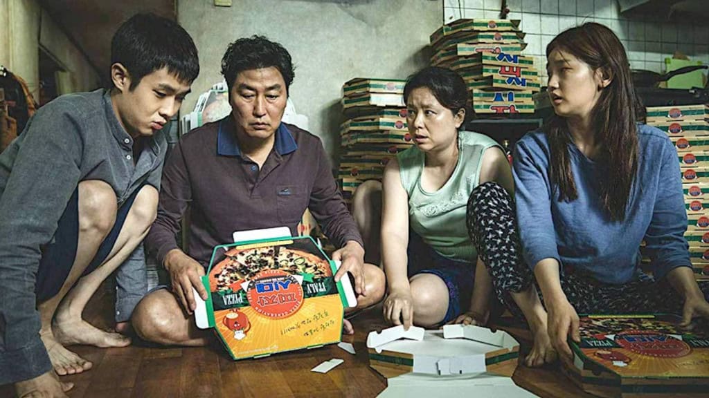 cena do filme Parasita, onde a família monta caixas de pizza em casa