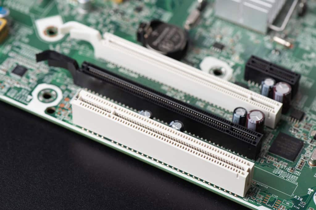 Detalhe dos slots PCIe e PCI na placa-mãe de um PC, ilustrando como a escolha correta desses conectores impacta a atualização de hardware e a compatibilidade dos componentes
