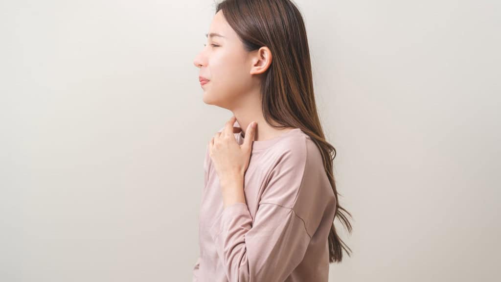 jovem com mão no pescoço indicando dor