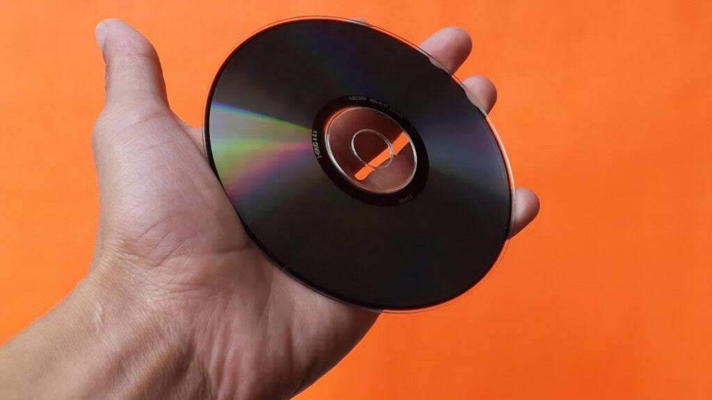 Mão segurando cd contra fundo laranja 