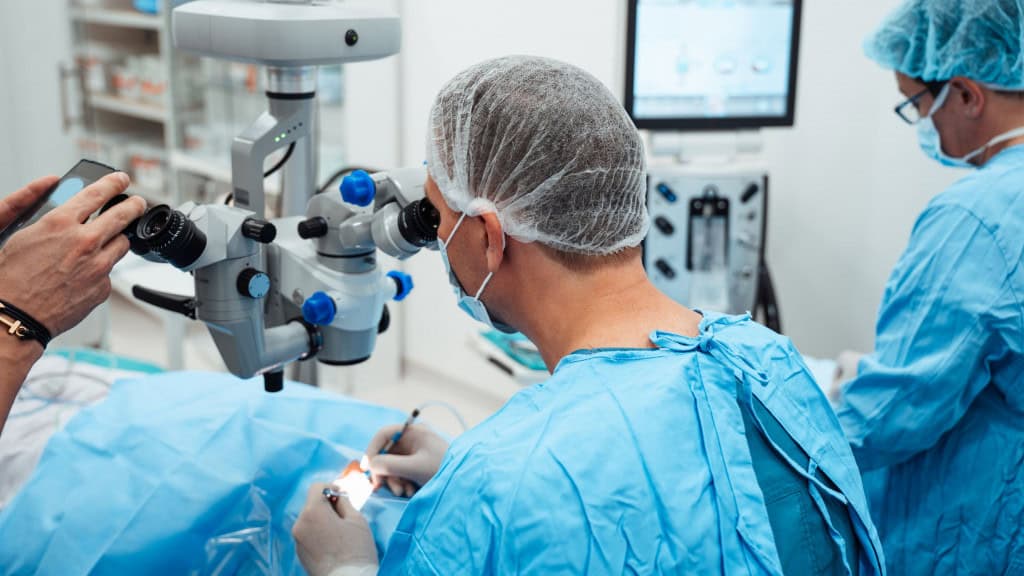 Médico fazendo cirurgia em olho com enfermeiros do lado