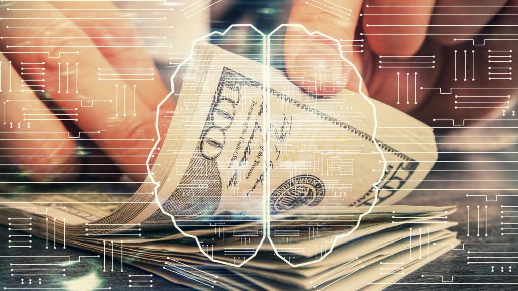Pessoa manuseando dinheiro (notas de dólar); imagem é sobreposta por ilustração de cérebro e tecnologia representando a inteligência artificial (IA)