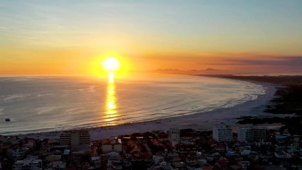 Cidade do Rio prova que pôr do sol pode melhorar o bem-estar O pôr do sol de Arraial do Cabo não virou apenas um cartão-postal lindo, ele é o cenário mais clicado do Brasil nas redes sociais, impulsionando o turismo digital e colocando essa cidade litorânea no radar de quem ama natureza, bem-estar e experiências memoráveis. Estudos publicados em revistas renomadas como a Journal of Environmental Psychology mostram como lugares como esse podem impactar no bem-estar de quem visita. Estudos revelam por que o pôr do sol de Arraial relaxa e melhora o humor